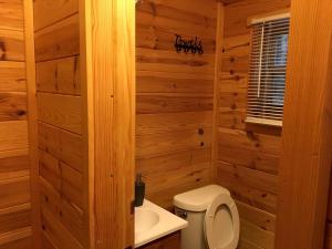 Un baño de madera con inodoro y lavabo. en Log Cabin for Family Glamping Vacation near Cherry Springs State Park, Pennsylvania, en Short Run