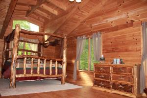 - une chambre dans une cabane en rondins avec un lit et une fenêtre dans l'établissement Deluxe Log Cabin with a Hot Tub in the Smoky Mountains of North Carolina, à Crabtree