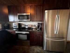 a kitchen with wooden cabinets and a stainless steel refrigerator at Scenic Vacation Home with Wrap-Around Deck Overlooking Ennis Lake near McAllister, Montana in Ennis