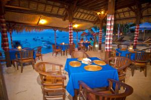 a blue table and chairs in a restaurant with a pool at Lumbung Bali Huts in Nusa Lembongan +35 photos