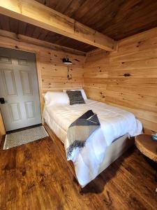 Un dormitorio con una cama en una cabaña de madera. en Pet-Friendly Tree Cabin with Lofted Space in Ohio, en Deersville