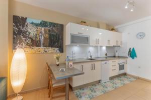 a kitchen with white cabinets and a table at Apartamento Calas in Puerto Naos