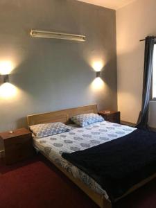 a bedroom with a bed with two night stands and lights at Durrani House in Dargai