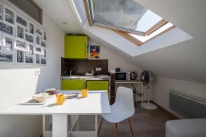 a kitchen with green cabinets and a white table and chairs at Studio sous les toits Annecy Centre-Ville in Annecy