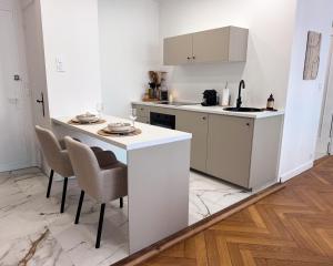 a kitchen with white cabinets and a table and chairs at La Suite Asmée - Centre-ville Lons-le-Saunier in Lons-le-Saunier +3 photos
