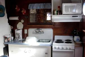 a small kitchen with a stove and a microwave at Secluded Cottage on East Ash Creek near Fort Robinson State Park, Nebraska in Whitney