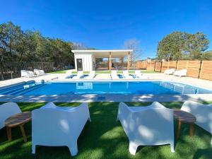 a swimming pool with white chairs and a swimming poolvisor at Pet-Friendly Glamping Cabin, with River Access in Ingram, Texas in Hunt