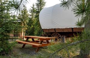 a picnic table and a white tent and a wagon at Charming Idaho Glamping Wagon with AC, Fire Pit & Breakfast | Bonners Ferry Escape in Bonners Ferry