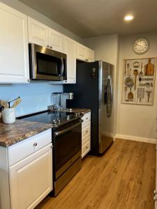 a kitchen with white cabinets and a black refrigerator at Secluded Modern Vacation Home with Madison Range Views near Ennis Lake, McAllister Montana in Ennis