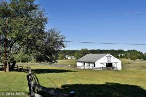 a white barn sitting in the middle of a field at Pleasant Cozy Airstream with Amazing Stargaze and Farm Views in Maryland in Seneca Highlands