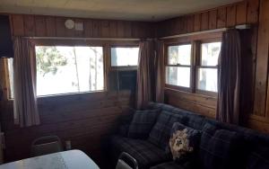 a living room with a couch and two windows at Lakeside Cabin Rental with a Boat Launch near Tomahawk, Wisconsin in Tomahawk +5 photos