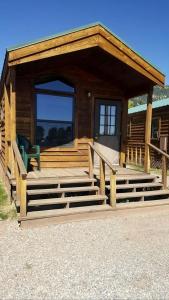a log cabin with stairs and a green chair on it at Comfortable Lakefront Cabin near West Yellowstone, Montana in Lakeview