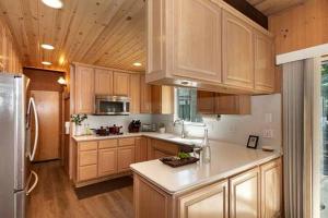 a kitchen with wooden cabinets and a stainless steel refrigerator at Spacious Modern Cabin Near Big Bear Lake in California in Big Bear City