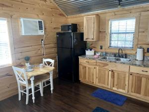 a kitchen with a table and a black refrigerator at Rustic Dog-Friendly Cabin with Private Deck and Hot-Tub in Texas in Wimberley
