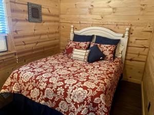 a bed in a room with a wooden wall at Rustic Dog-Friendly Cabin with Private Deck and Hot-Tub in Texas in Wimberley