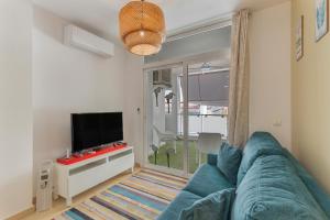 a living room with a blue couch and a flat screen tv at Apartamento Calas in Puerto Naos