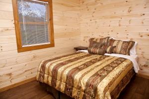 Un dormitorio con una cama en una cabaña de troncos en Pretty Cabin with Hot-tub in Herod, Illinois, en Karbers Ridge