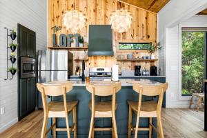 une cuisine avec des boiseries et un îlot bleu avec des tabourets de bar dans l'établissement Amazing Secluded Cabin Perfect for Couples in Broken Bow, Oklahoma, à Stephens Gap