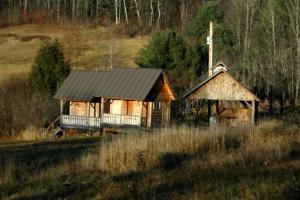 a wooden cabin with a black roof in a field at Rustic Vacation Rental on a Beautiful Working Farm in Royalton, Vermont in South Royalton