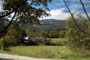 a house in the middle of a field with trees at Rustic Vacation Rental on a Beautiful Working Farm in Royalton, Vermont in South Royalton