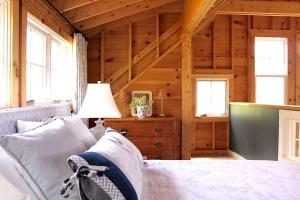 Habitación con cama, lámpara y ventanas. en Rustic Chic Maine Cabin @ Diagonair near Sedgwick, Maine, en Brooksville