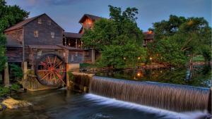 ein Haus mit einem Wasserrad davor in der Unterkunft Brand-New Luxury Cabin with Game Room & Hot Tub near Downtown Gatlinburg, TN in Chalet Village