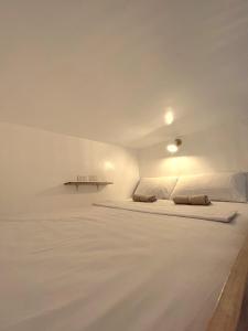 ein weißes Zimmer mit einem Bett und einem Tisch in der Unterkunft Blau Hostel in El Nido
