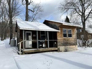 une petite cabane en rondins avec de la neige au sol dans l'établissement Portage Lakeside Cabins in Portage Lake, ME, à Portage Lake Municipal Seaplane Base