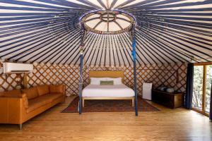 a room with a bed and a couch in a yurt at Secluded Romantic Yurt with Hot Tub in Wimberley, Texas in Cloptins Crossing