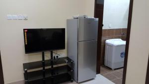 a flat screen tv sitting next to a refrigerator at Golden Seasons Furnished Apartment - 2 in Salalah
