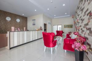 a living room with red chairs and a counter at Capital O 94770 Hotel Astra Novilia in Makassar