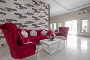 a living room with a red couch and two chairs at Capital O 94770 Hotel Astra Novilia in Makassar