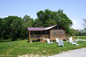Una cabaña de madera con sillas y un porche. en Entire Three Cabins Property Perfect for Big Groups in Marion, Illinois, en Sunset Harbor