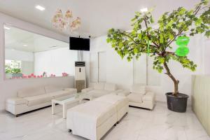a living room with white furniture and a potted tree at Capital O 94792 Aleander Hotel in Jakarta