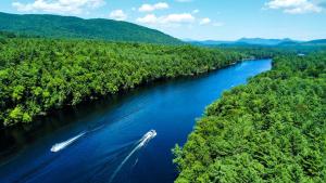 a boat traveling down a river in the woods at Luxury Canvas Group Glamping Tent | Adirondacks in Corinth, NY in Corinth