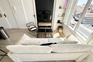 a living room with a white couch and a tv at Seaside getaway serenity and comfort in Palavas-les-Flots