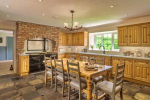 cocina con mesa de madera, sillas y chimenea en Finest Retreats - Grassyards House, en Skelmorlie
