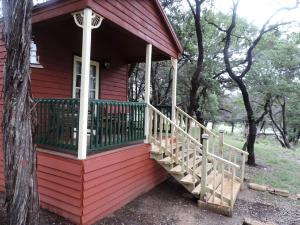 a red house with a porch with a wooden staircase at Cozy and Comfortable Cabin Rental Just 15 Minutes from San Antonio, Texas in Kreutzberg