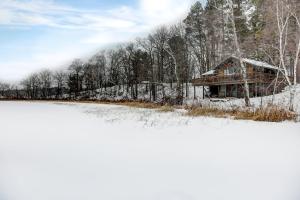 a log cabin in the snow next to a lake at Stunning Cabin Getaway Surrounded by Towering Pine Trees in Walker, Minnesota in Ah-gwah-ching