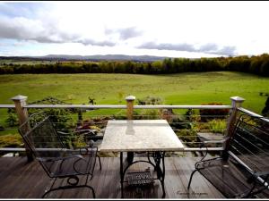 a table and chairs on a deck with a view of a field at Idyllic Cottage Rental near Mount Mansfield State Forest, Vermont in Hardwick