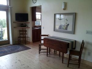 a living room with a table and chairs and a television at Idyllic Cottage Rental near Mount Mansfield State Forest, Vermont in Hardwick +6 photos