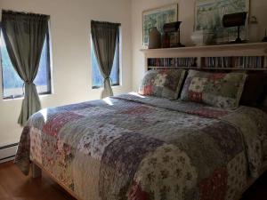 a bedroom with a bed and two windows at Impressive Cabin with a Pool and Hot Tub Ideal for Weekend Getaways in the Catskills in Tannersville