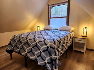 une chambre avec un lit avec une couette et une fenêtre dans l'établissement Secluded Luxury Cabin with Hot Tub on 10 Private Acres near Trails in Reed City, Michigan, à Idlewild