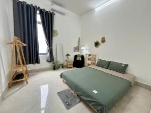 a bedroom with a green bed in a room at Nhi Homestay Rạch Giá in Rach Gia