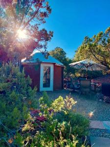 a garden with a red shed and an umbrella at Charming Yurt in the Cibola National Forest near Albuquerque, New Mexico in Tijeras