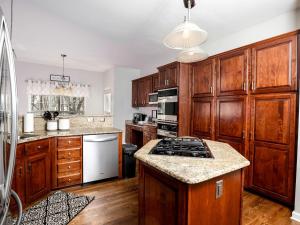 une cuisine avec des armoires en bois et un four à plaques de cuisson dans l'établissement Fantastic Cottage with Fire Pit and Barbecue in Charlotte, North Carolina, à Charlotte 56 autres photos