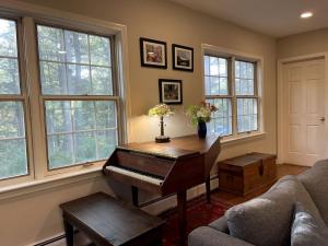 a living room with a piano in a room with windows at Unique Ski Rental in Berkshires Charlemont Near Hawley State Forest, Plainfield, Western Massachusetts in Plainfield