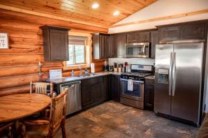 a kitchen with a table and a stainless steel refrigerator at Luxury Pet-Friendly 1-Bedroom Log Cabin in Bonners Ferry with Full Kitchen and Wi-Fi in Bonners Ferry +4 photos
