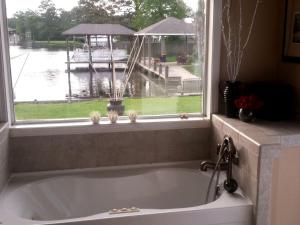 a bath tub in a bathroom with a window at Beautiful Waterfront Cottage Rental with a Pool near New Orleans, Louisiana in Slidell +2 photos
