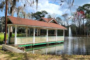 ein Pavillon inmitten eines Teiches mit Springbrunnen in der Unterkunft Quaint Cottage with Covered Dock on the Pond and Walking Trails in Georgia in Midway